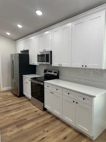 kitchen with white cabinetry, light countertops, light wood-style flooring, and appliances with stainless steel finishes