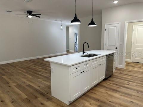 kitchen featuring ceiling fan, light wood-type flooring, dishwasher, a sink, and baseboards