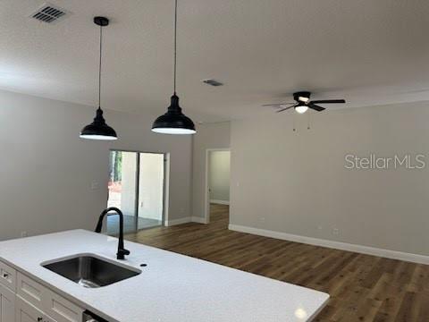 kitchen with a sink, light countertops, a ceiling fan, dark wood finished floors, and white cabinetry
