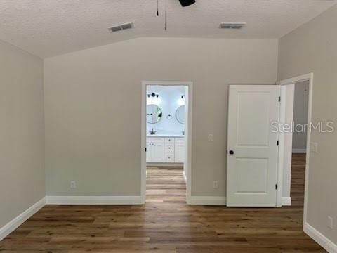 spare room featuring a textured ceiling, vaulted ceiling, and wood finished floors