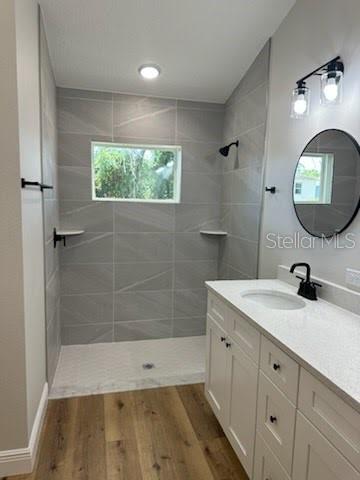 bathroom with a walk in shower, vanity, and wood finished floors