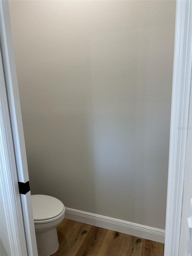bathroom featuring baseboards, toilet, and wood finished floors