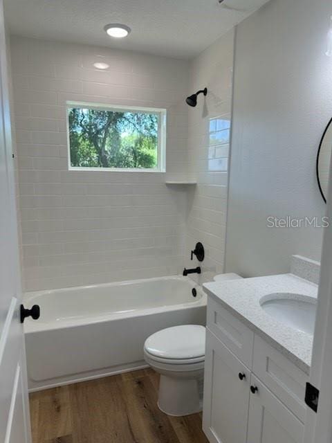 bathroom with toilet, shower / bath combination, wood finished floors, and vanity
