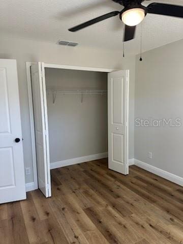unfurnished bedroom featuring a closet, visible vents, baseboards, and wood finished floors
