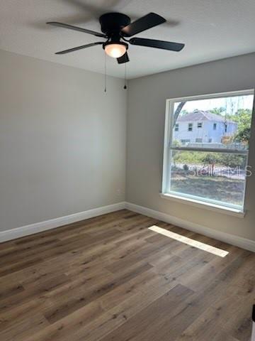 unfurnished room featuring wood finished floors, ceiling fan, and baseboards