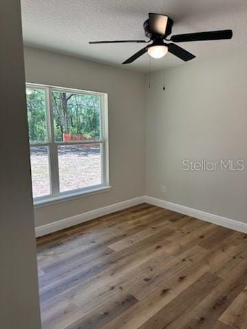 spare room featuring wood finished floors, ceiling fan, and baseboards