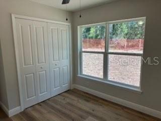 unfurnished bedroom featuring dark wood finished floors, baseboards, and multiple windows