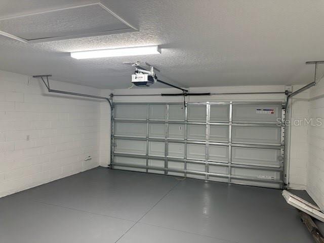 garage featuring a garage door opener and concrete block wall