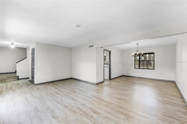 unfurnished living room with stairs, light wood-style flooring, a chandelier, and visible vents