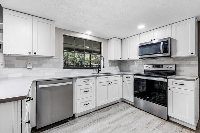 kitchen with a sink, white cabinetry, decorative backsplash, and appliances with stainless steel finishes
