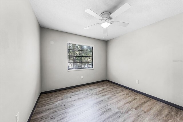 empty room featuring baseboards, a textured ceiling, wood finished floors, and a ceiling fan