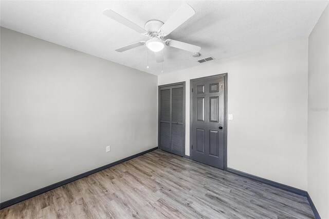 unfurnished bedroom featuring light wood-type flooring, baseboards, a textured ceiling, visible vents, and a closet