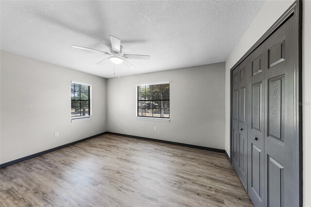 unfurnished bedroom with baseboards, a closet, light wood-style floors, and a textured ceiling