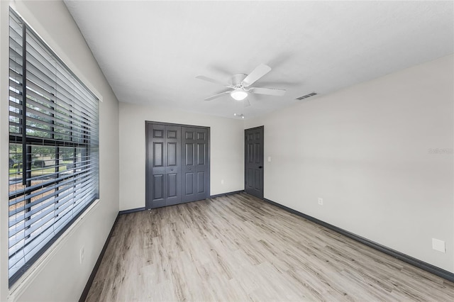 unfurnished bedroom featuring a closet, visible vents, baseboards, ceiling fan, and light wood-style floors