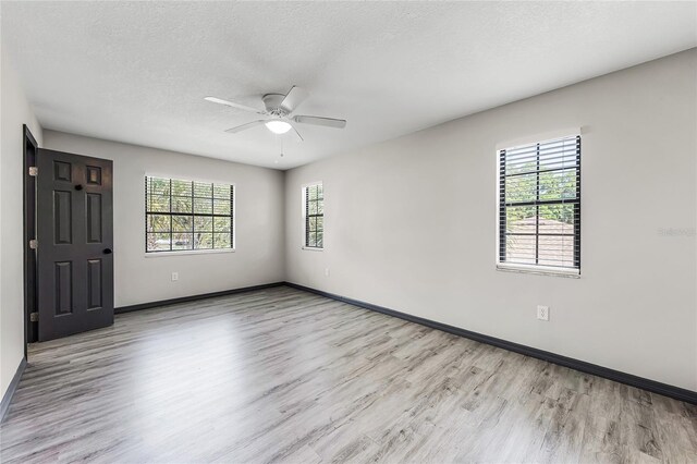 spare room featuring baseboards, a textured ceiling, wood finished floors, and a ceiling fan
