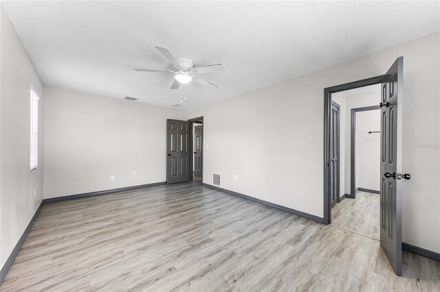 spare room with baseboards, visible vents, light wood-style flooring, and ceiling fan