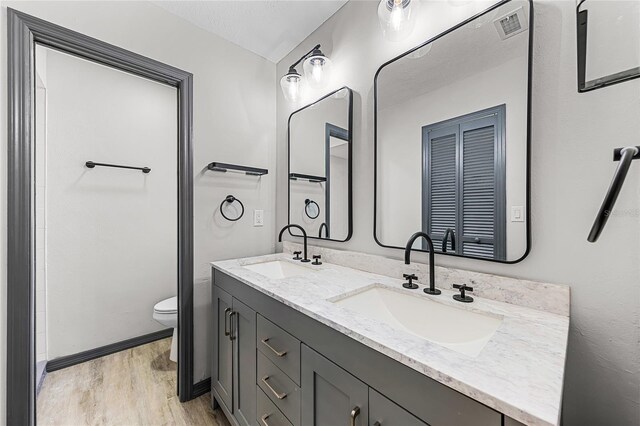bathroom featuring visible vents, a sink, toilet, and wood finished floors