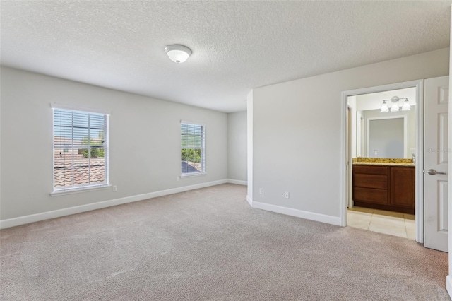8639 Lower Villagewalk Cir, Orlando, FL 32827 - unfurnished bedroom with light colored carpet, baseboards, a textured ceiling, and ensuite bath