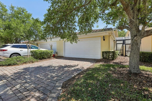 8639 Lower Villagewalk Cir, Orlando, FL 32827 - view of front of home with decorative driveway, a garage, stucco siding, and a tiled roof