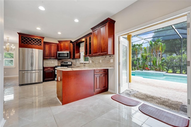 12706 Magnolia Bay Blvd, Clermont, FL 34711 - kitchen featuring stainless steel appliances, a peninsula, backsplash, recessed lighting, and light tile patterned floors