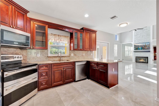 12706 Magnolia Bay Blvd, Clermont, FL 34711 - kitchen featuring appliances with stainless steel finishes, decorative backsplash, a peninsula, and light stone countertops