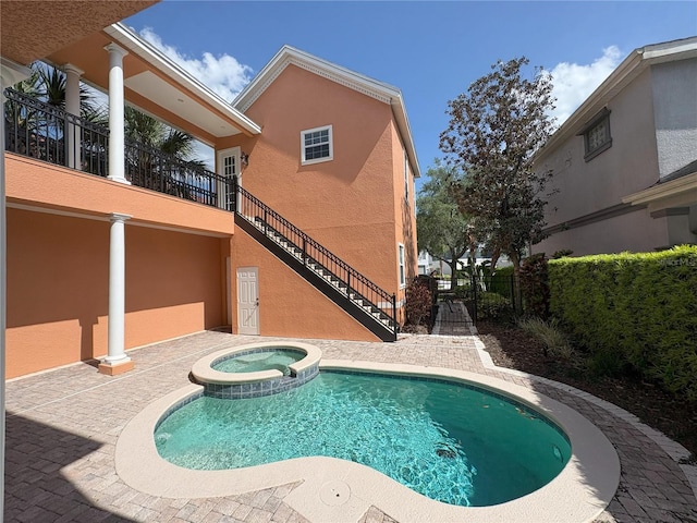 back of house featuring a pool with connected hot tub, stucco siding, a patio, fence, and stairs