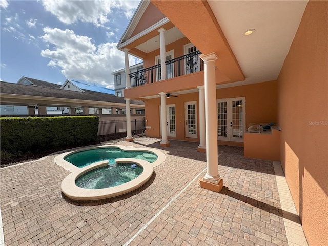view of swimming pool with a patio area, a pool with connected hot tub, french doors, and fence
