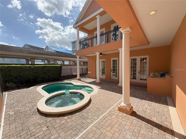 view of pool with a patio, a pool with connected hot tub, french doors, and fence
