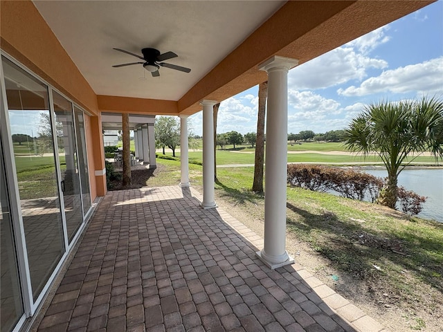 view of patio with a water view and a ceiling fan