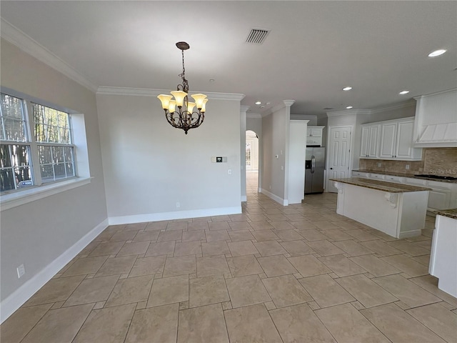kitchen featuring ornamental molding, white cabinets, stainless steel refrigerator with ice dispenser, a notable chandelier, and backsplash