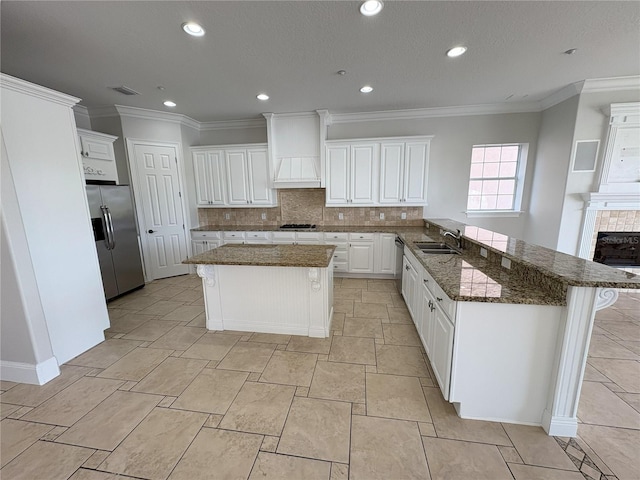 kitchen with a peninsula, premium range hood, white cabinetry, and appliances with stainless steel finishes