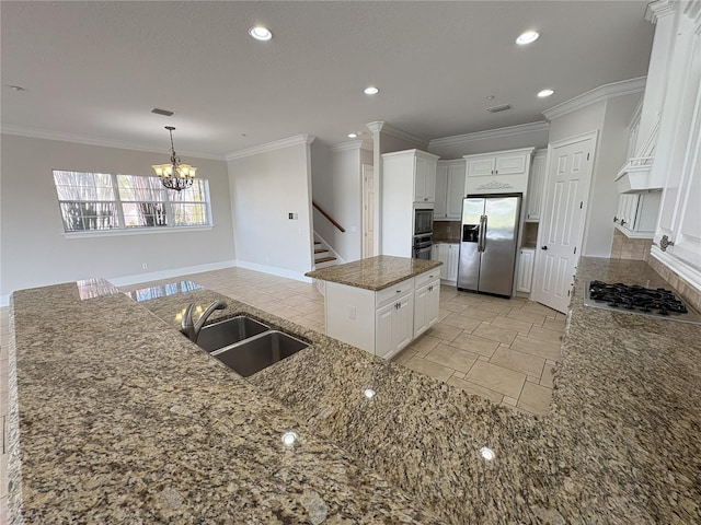 kitchen with an inviting chandelier, stone counters, a kitchen island, a sink, and stainless steel appliances