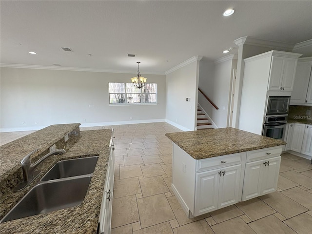 kitchen featuring white cabinets, a notable chandelier, a sink, and appliances with stainless steel finishes