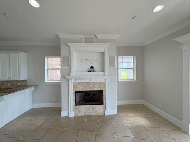 unfurnished living room featuring a healthy amount of sunlight, a tiled fireplace, and ornamental molding