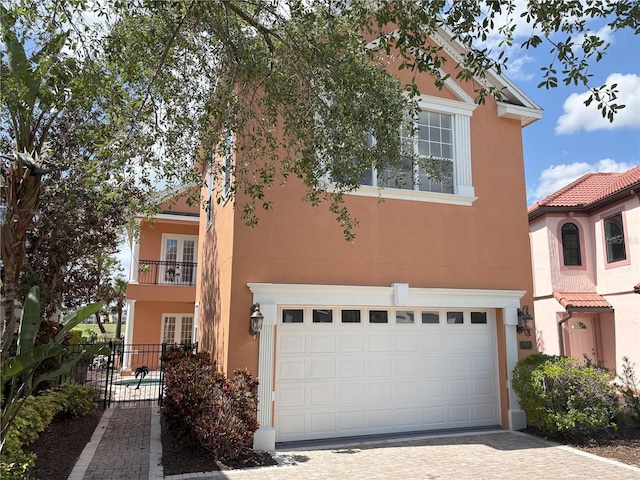 view of front of property with a garage, decorative driveway, stucco siding, and fence
