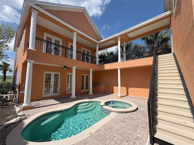 rear view of house with a pool with connected hot tub, a patio, a balcony, french doors, and stucco siding