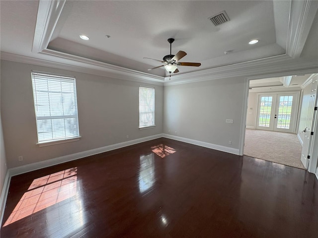 spare room featuring visible vents, a raised ceiling, a ceiling fan, dark wood finished floors, and crown molding