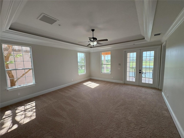 carpeted spare room with visible vents, baseboards, ceiling fan, crown molding, and a tray ceiling