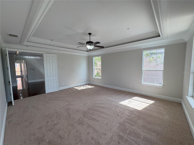 unfurnished bedroom featuring baseboards, crown molding, carpet floors, visible vents, and a tray ceiling