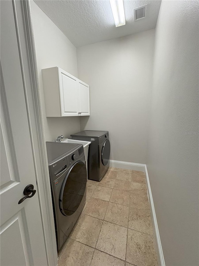 clothes washing area featuring cabinet space, a textured ceiling, visible vents, baseboards, and washing machine and dryer