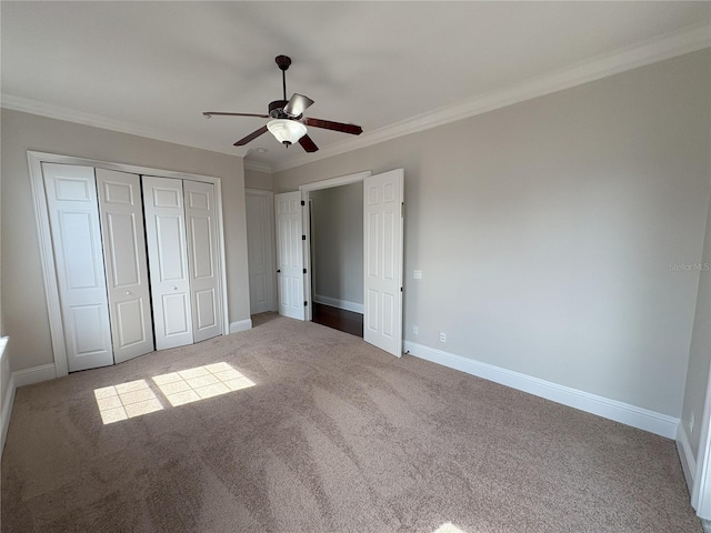 unfurnished bedroom featuring crown molding, a closet, baseboards, and carpet floors