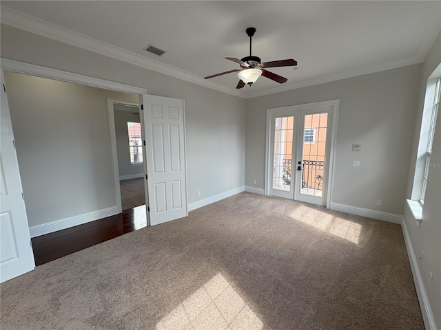 carpeted spare room with baseboards, ornamental molding, french doors, visible vents, and ceiling fan