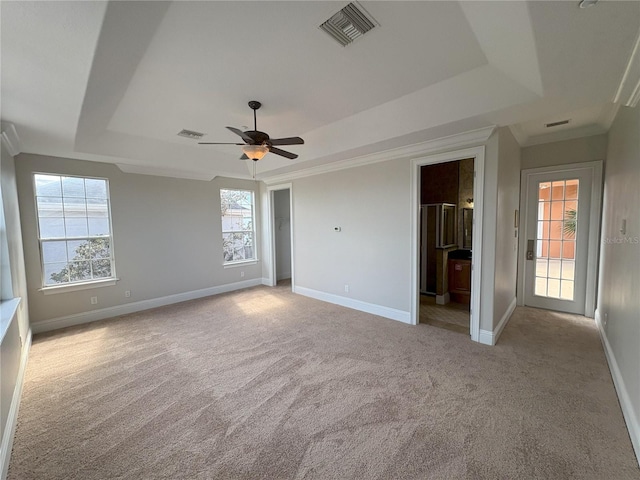 unfurnished bedroom with a tray ceiling, baseboards, carpet, and visible vents