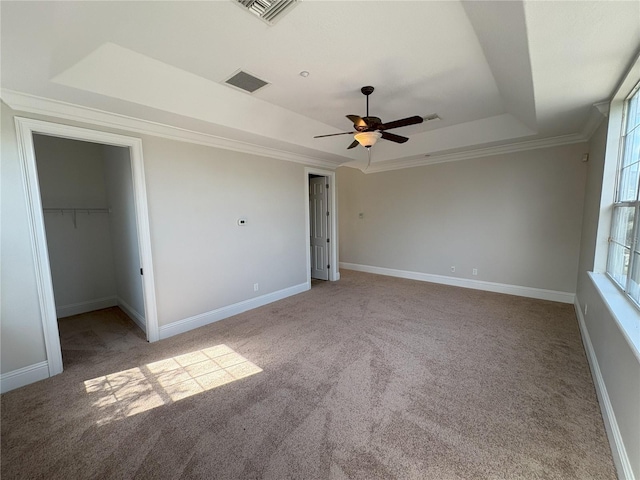 unfurnished bedroom featuring visible vents, a tray ceiling, baseboards, and carpet floors