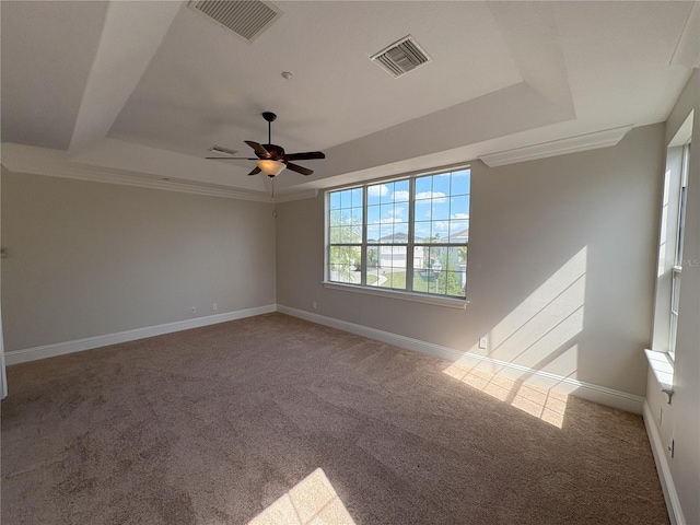 carpeted spare room with visible vents, baseboards, and a raised ceiling