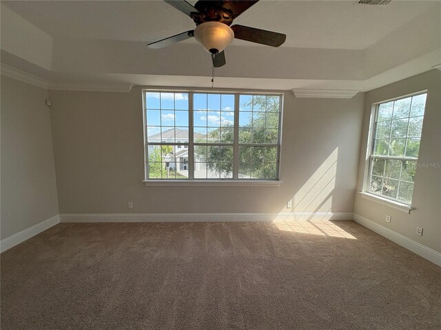 carpeted spare room with a tray ceiling, ceiling fan, baseboards, and visible vents