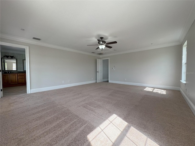 empty room with ornamental molding, baseboards, a ceiling fan, and light colored carpet