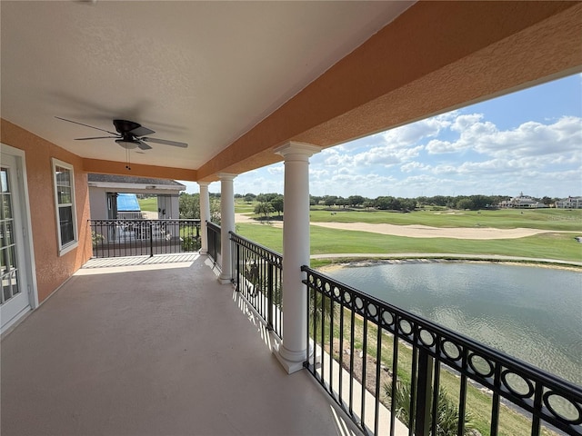 balcony with view of golf course, a water view, and ceiling fan