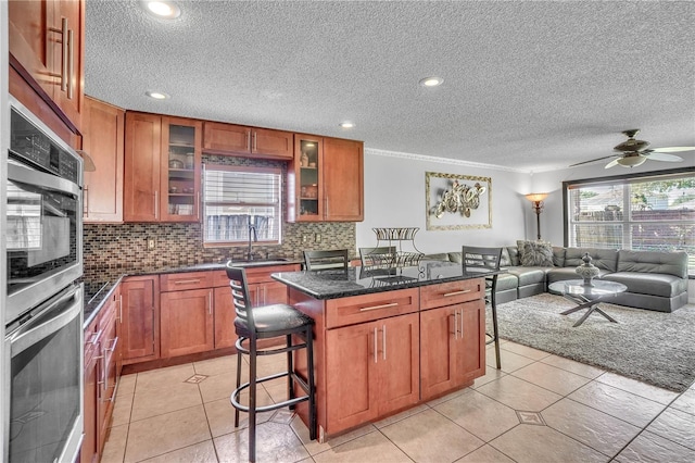 kitchen featuring brown cabinets, open floor plan, backsplash, and a kitchen breakfast bar