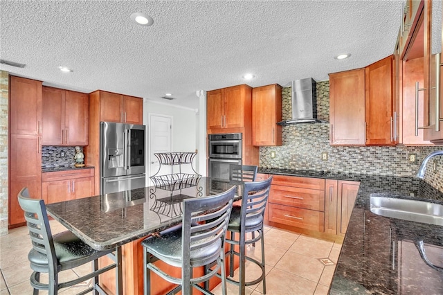 kitchen with wall chimney range hood, a sink, light tile patterned flooring, and appliances with stainless steel finishes